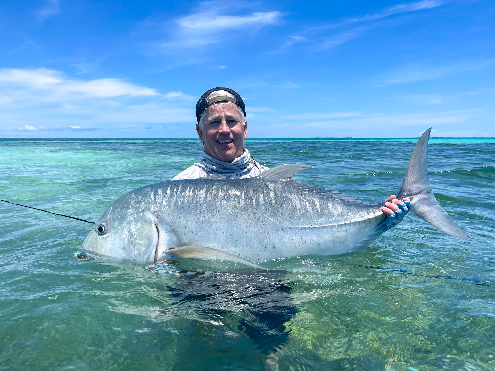 Fisherman holding a monster of giant trevally at Cosmoledo Atoll