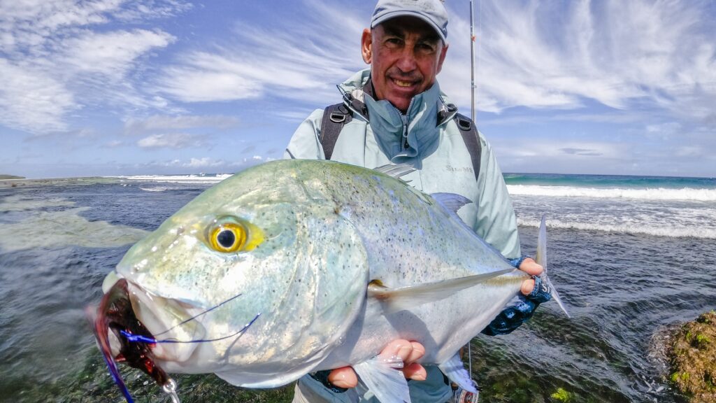 Man holding huge bluefin trevally measuring a lot