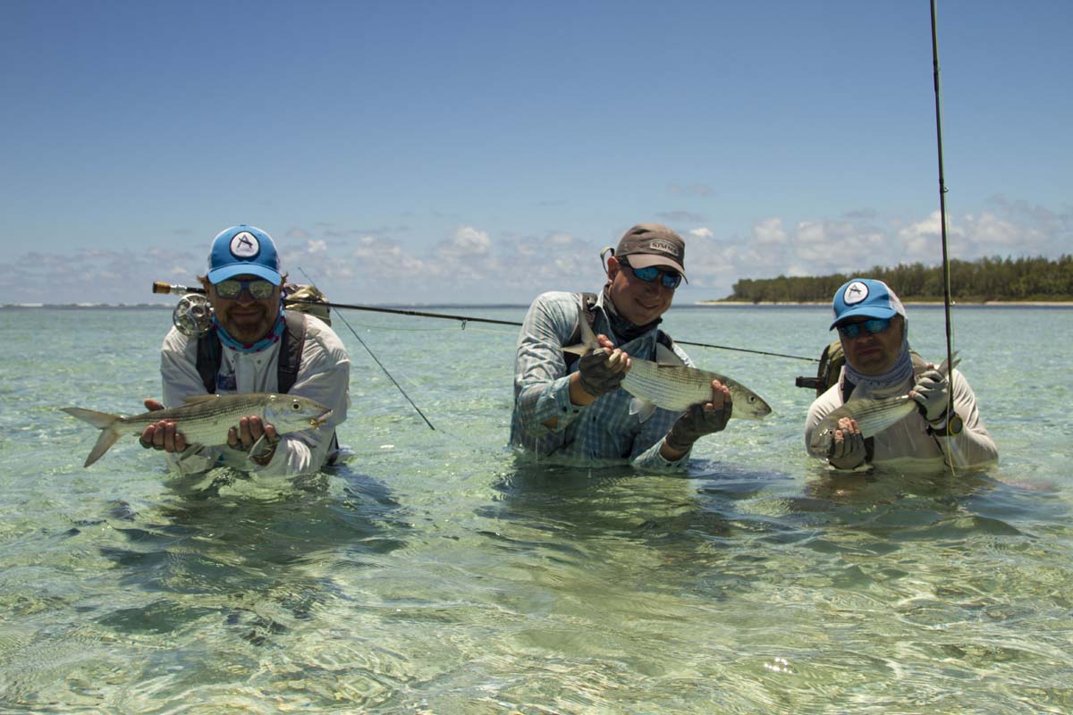 Anglers in a crystal clear lagoon showing off their catches