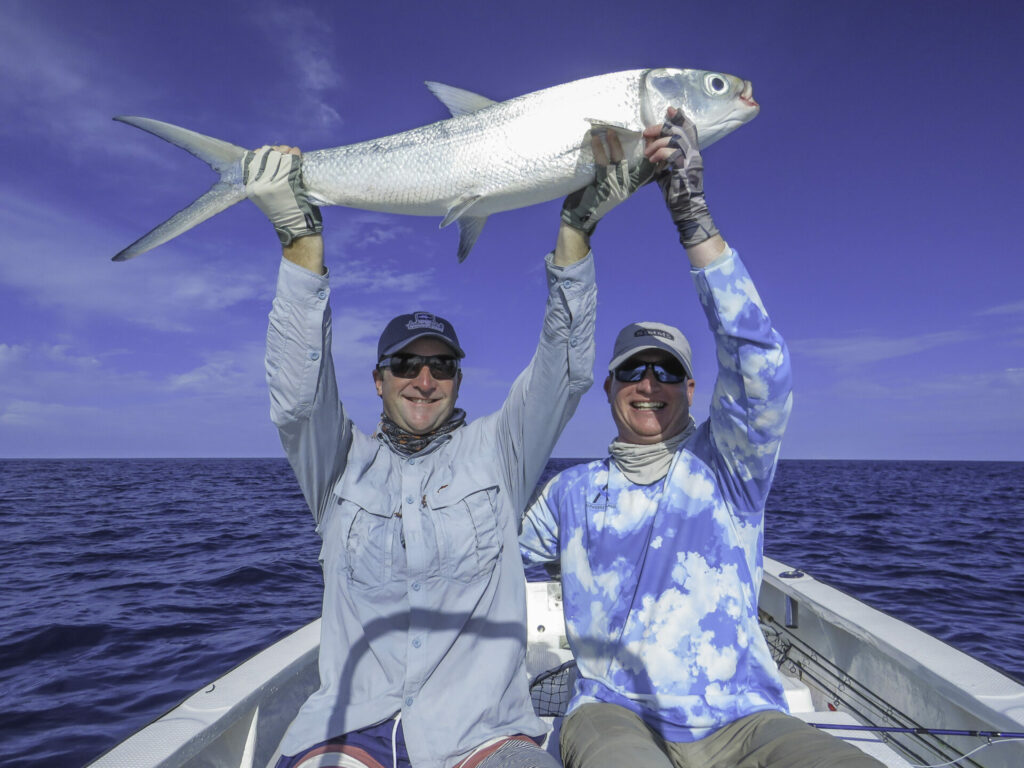 Fly fishermen hold a fish at wild Astove Atoll