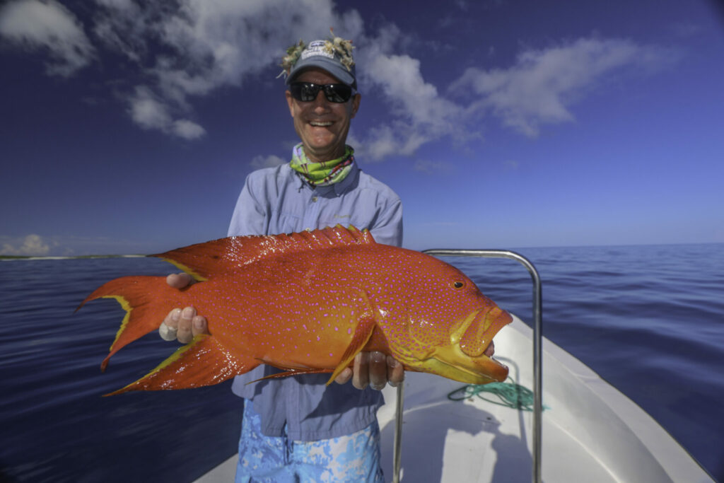 Fly fishermen at wild Astove Atoll holding his catch